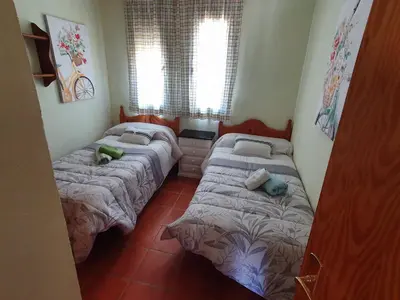 a bedroom with two beds and two windows at Coto la Campa in Chiclana de la Frontera