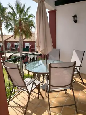 a patio with a glass table and chairs and a umbrella at Coto la Campa in Chiclana de la Frontera
