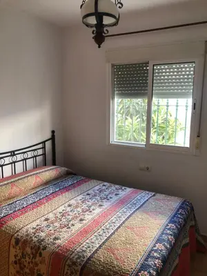 a bedroom with a bed and two windows at Casas Juani- chalet con piscina in Conil de la Frontera