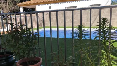 a fence with plants and a swimming pool at Casas Juani- chalet con piscina in Conil de la Frontera