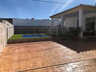 a house with a fence and a patio at Casas Juani- chalet con piscina in Conil de la Frontera