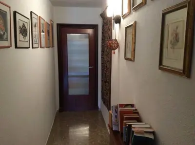 a hallway with a door and a shelf with books at Homestay en Plaza Candelaria, Casco Antiguo in Cádiz