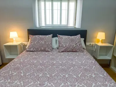 a bedroom with a bed with a purple comforter and two lamps at Apartamento Plaza Viuda in Cádiz