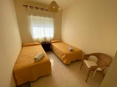 a bedroom with two beds and a chair and a window at Apartamento en Bahia Golf - Costa Ballena in Costa Ballena