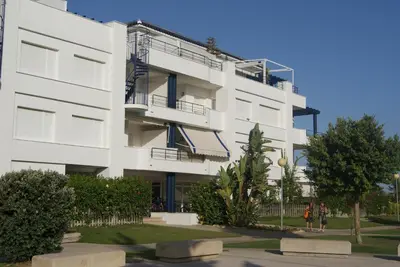 a white building with people walking in front of it at Apartamento en Bahia Golf - Costa Ballena in Costa Ballena