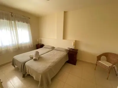 a bedroom with a bed and a chair and a window at Apartamento en Bahia Golf - Costa Ballena in Costa Ballena