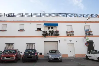 a white building with cars parked in a parking lot at Miriam Costa de la luz in Jerez de la Frontera