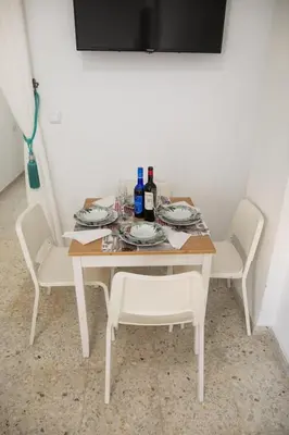 a white table with two chairs and bottles of wine at Miriam Costa de la luz in Jerez de la Frontera