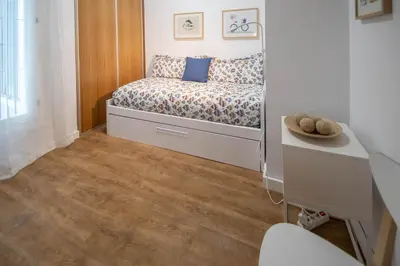 a small bedroom with a bed and a desk at Duplex Flamingo Cadiz in Cádiz