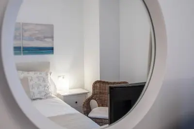 a mirror reflecting a bedroom with a bed and a chair at Duplex Flamingo Cadiz in Cádiz