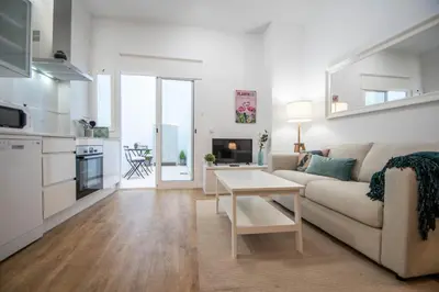 a white living room with a couch and a table at Duplex Flamingo Cadiz in Cádiz