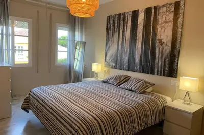 a bedroom with a bed with two lamps and a painting on the wall at VIVE JEREZ Casa de lujo con piscina y barbacoa en la mejor zona de Jerez de la Frontera in Jerez de la Frontera