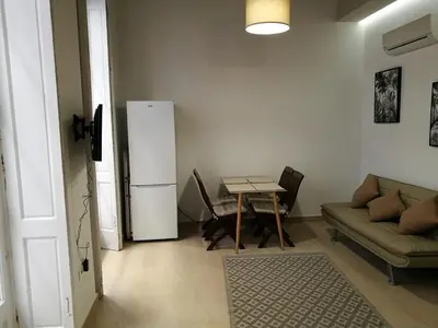 a living room with a table and a refrigerator at Apartamentos Valverde Cádiz 1-B in Cádiz