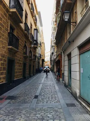 a cobblestone street with people walking down the street at Apartamentos Valverde Cádiz 1-C in Cádiz