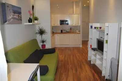 a living room with a green couch and a kitchen at Bonito apartamento Cádiz centro in Cádiz