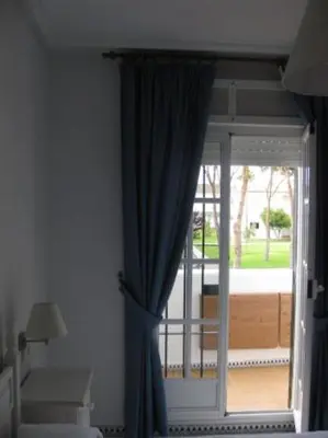 a window with a blue curtain in a room at Apartamento La Barrosa, Chiclana in Chiclana de la Frontera