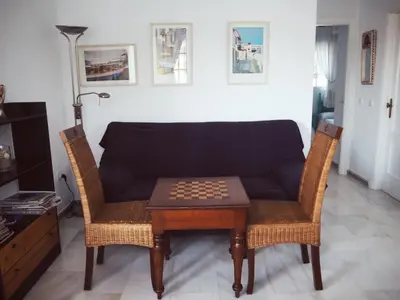 a living room with a couch and a chessboard on a table at Apartamento La Barrosa, Chiclana in Chiclana de la Frontera