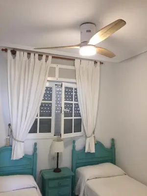 a bedroom with two beds and a ceiling fan at Apartamento La Barrosa, Chiclana in Chiclana de la Frontera