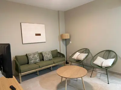 a living room with a green couch and two chairs at Apartamentos Turísticos La Terraza* in Las Cabezas de San Juan