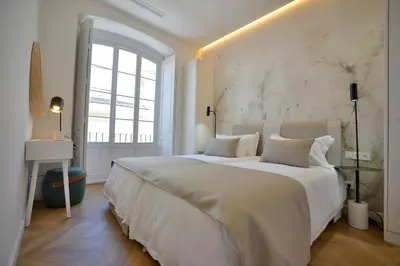 a white bedroom with a large bed and a window at Plaza Mina Suites - Adults Recommended by Luxury Suites Cadiz in Cádiz