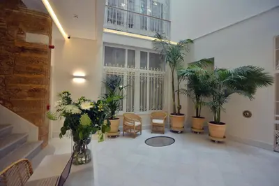 a room with potted plants and chairs in a building at Plaza Mina Suites - Adults Recommended by Luxury Suites Cadiz in Cádiz