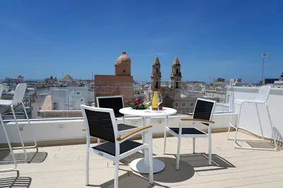 a balcony with a table and chairs on a roof at Plaza Mina Suites - Adults Recommended by Luxury Suites Cadiz in Cádiz