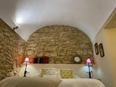 a bedroom with a stone wall with a bed and two lamps at Casa Arco de la Pastora in Medina Sidonia