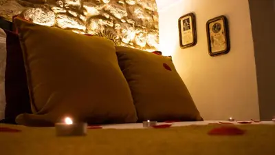 a couch with two pillows and a candle on it at Casa Arco de la Pastora in Medina Sidonia