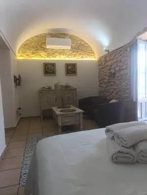 a bedroom with a bed and a stone wall at Casa Arco de la Pastora in Medina Sidonia