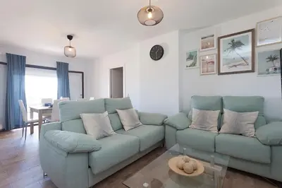 a living room with a blue couch and a table at APARTAMENTO VIRGEN DEL CARMEN in Chipiona