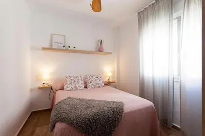 a bedroom with a bed with two pillows and a window at APARTAMENTO VIRGEN DEL CARMEN in Chipiona