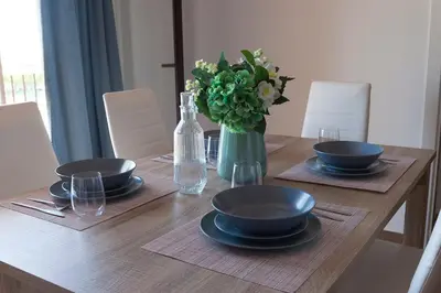 a wooden table with plates and a vase of flowers at APARTAMENTO VIRGEN DEL CARMEN in Chipiona