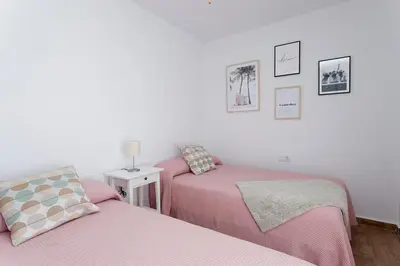 two beds in a small room with pink sheets at APARTAMENTO VIRGEN DEL CARMEN in Chipiona