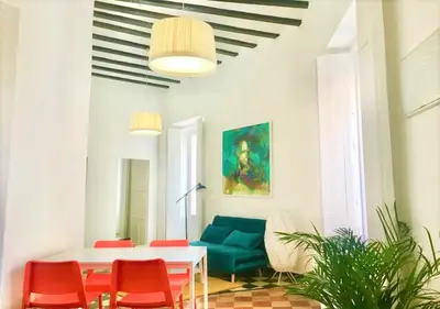 a living room with a white table and red chairs at Sol de Cádiz in Cádiz