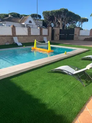 a pool with a slide and two chairs on the grass at La Quinta - La Barrosa in Chiclana de la Frontera