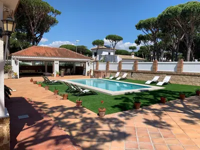 a swimming pool with lawn chairs and a house at La Quinta - La Barrosa in Chiclana de la Frontera