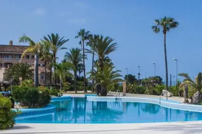 a large swimming pool with palm trees and a building at Duplex 6 pax con Wifi en Bahia Sur con parking y piscinas comunitarias in San Fernando