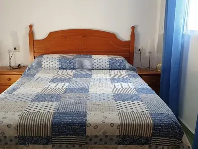 a bed with a blue and white quilt on it at Pinar de Don Jesus Sagitario in Campano