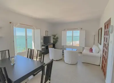 a living room with a table and white chairs at Magnífico alojamiento a 3 metros de la playa y en la Plaza del Castillo in Chipiona