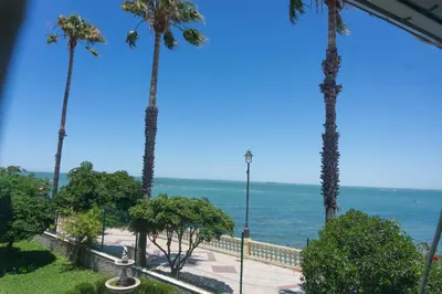 a view of the ocean from a resort with palm trees at Magnífico alojamiento a 3 metros de la playa y en la Plaza del Castillo in Chipiona
