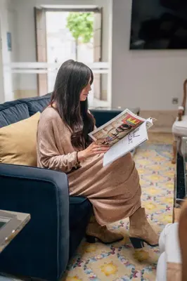 a woman sitting on a couch reading a magazine at Hotel Boutique Palacio Corredera in Jerez de la Frontera