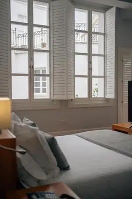 a bedroom with three windows and a bed and a bed sidx sidx at Hotel Boutique Palacio Corredera in Jerez de la Frontera