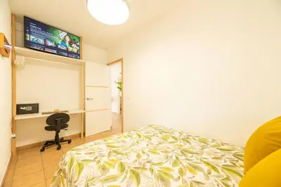 a bedroom with a bed and a desk and a television at Apartamento Playa La Barrosa in Chiclana de la Frontera