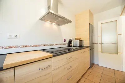 a kitchen with wooden cabinets and a stove top oven at Apartamento Playa La Barrosa in Chiclana de la Frontera