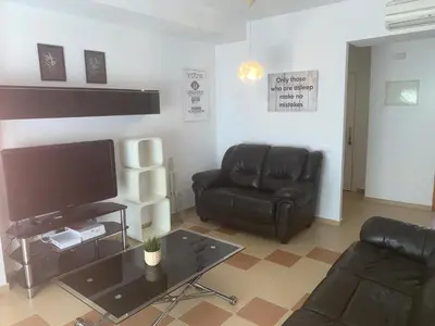 a living room with black leather furniture and a flat screen tv at El Anfitrión - Mirador de los Navegantes in Sanlúcar de Barrameda
