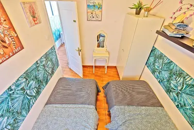 a room with two beds and a chair at Plaza de Toros 3-Bedroom Apartment with Balcony in El Puerto de Santa María