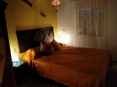 a bedroom with a bed with an orange comforter and a window at Villa casa blanca luxury spa con piscina privada y jacuzzi privado in Chiclana de la Frontera