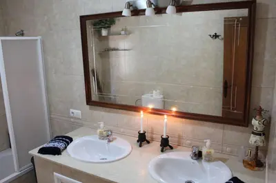 a bathroom with two sinks and a mirror and candles at Villa andaluza en zona Playa Barrosa con piscina y barbacoa in Chiclana de la Frontera