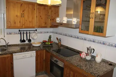 a kitchen with wooden cabinets and a counter top at Villa andaluza en zona Playa Barrosa con piscina y barbacoa in Chiclana de la Frontera