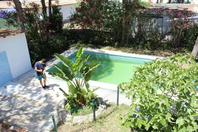 a man standing next to a swimming pool at Villa andaluza en zona Playa Barrosa con piscina y barbacoa in Chiclana de la Frontera